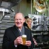 Bundeskanzler Olaf Scholz (SPD) hat bei seinem Besuch bei der Brauerei Gold Ochsen in Ulm ein Glas Bier in der Hand.
