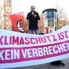 Ein Demonstrant spricht hinter einem Banner mit der Aufschrift «Klimaschutz ist kein Verbrechen».