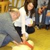 Bürgermeister Paul Wecker sucht den Druckpunkt für die Herzdruckmassage, Sabine Sciuk hält den Defibrillator bereit.