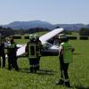 Einsatzkräfte der Feuerwehr stehen an einem Kleinflugzeug am Flugplatz in Durach.