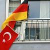 An einem Fenster wehen in München eine deutsche und eine türkische Fahne.