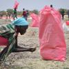 Eine Frau sammelt Hirse vom Boden auf, die in Säcken von Mitarbeitern des Welternährungsprogramms der Vereinten Nationen über Kandak im Südsudan abgeworfen wurde.