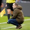 Augsburgs Trainer Manuel Baum hockt beim Spiel in Mönchengladbach an der Seitenlinie.