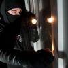 Ein vermummter Einbrecher mit Taschenlampe. Foto: Andreas Gebert/dpa +++(c) dpa - Bildfunk+++