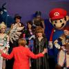 Super-Merkel trifft unter anderem Super-Mario: Auf der Messe Gamescom in Köln lernt die Kanzlerin neue Figuren kennen. Eigentlich sind sie virtuell, aber bei der Schau werden sie von Menschen verkörpert. 	 	