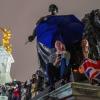 Menschen versammeln sich mit Regenschirmen und Flaggen, um Königin Elizabeth II. die letzte Ehre zu erweisen.