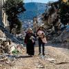 Eine Frau und ein Mann gehen im türkischen Hatay durch die Trümmer.