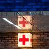 Leuchtkasten mit einem roten Kreuz vor der Notaufnahme eines Krankenhauses.