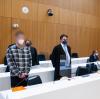 Die beiden wegen Mordes angeklagten Männer (links und zweiter von rechts) stehen vor Beginn der Verhandlung mit ihren Anwälten im Sitzungssaal.