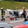 Die Vorderseite eines BMWs blieb auf der Fahrspur nach München liegen. Ein Feuerwehrmann begutachtet das Wrack. 	