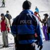 Ein Polizist kontrolliert, ob Skifahrer am Fuße einer Piste im Wallis ihre Masken tragen. 