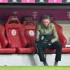 Münchens Trainer Julian Nagelsmann vom FC Bayern München sitzt in der Halbzeit auf der Trainerbank und schaut auf einen Bildschirm.