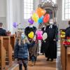 Beim Auszug vom eingeführten Pfarrer Andy Gatz (links) halten seine Kinder die mit Wünschen versehenen Luftballons.