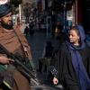 Ein Taliban-Kämpfer steht in Kabul Wache, während eine Frau vorbeiläuft. (Archivbild)