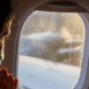 Ein weiblicher Fluggast mit Maske schaut vor dem Start aus dem Fenster. Auf Flügen von und nach Deutschland muss weiter Maske getragen werden.