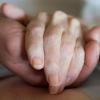 Ein Pfleger hält die Hand einer schwer kranken Frau: Ein Augsburger Arzt hilft Menschen, die nicht mehr weiterleben wollen, beim Suizid.