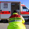 Ein Mann sitzt vor einem Rettungswagen der Feuerwehr.