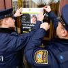 Polizisten hängen das Plakat zum Cold-Case von Claudia Obermeier an einer Glasscheibe auf.
