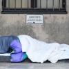 Ein trauriges Bild, das gerade in Großstädten oft zu sehen ist: Ein Obdachloser schläft in Decken und Schlafsäcke gehüllt unter einem Verbotsschild mit der Aufschrift "Lagern verboten".