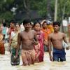 In Asien ist der Monsun in diesem Jahr besonders heftig ausgefallen. Menschen im indischen Agartala bringen sich auf einer vom Hochwasser überfluteten Straße in Sicherheit.