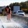 Ein Arbeiter säubert den Mittelstreifen auf der Baustelle an der B2 bei Donauwörth, während Autos nah an ihm vorbeifahren.