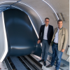 Markus Blume und Markus Söder bei der Eröffnung der Hyperloop-Teststrecke (links). Edmund Stoiber mit einem Transrapid-Modell (rechts oben) und Andreas Scheuer mit dem Modell einer Magnetschwebebahn (rechts unten).