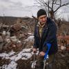Andrii Cherednichenko (50), der von einer Landmine verletzt wurde, steht auf Krücken vor den Ruinen seines Hauses im ukrainischen Kamjanka.