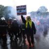 Rettungskräfte und ein Demonstrant mit einem Plakat mit der Aufschrift «Macron, Räuber der Armen» marschieren während einer Demonstration anlässlich des Tages der Arbeit in Paris.