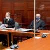 Die Angeklagten und ihre Anwälte sitzen vor Prozessbeginn im Sitzungssaal im Landgericht.