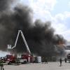 Im Augsburger Stadtteil Inningen steht am Montag eine Gewerbehalle in Flammen. Zahlreiche Feuerwehrleute kämpfen gegen die Flammen. Der Rauch ist von weitem zu sehen.