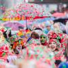 Karnevalisten sind komplett mit nassem Konfetti bedeckt und feiern die Eröffnung des Straßenkarnevals in Köln.