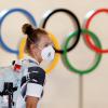 Eine deutsche Athletin trägt eine Schutzmaske und geht bei ihrer Ankunft am Flughafen Haneda an den Olympischen Ringen vorbei.