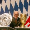 Der damalige FCB-Präsident, Franz Beckenbauer, steht zwischen Meisterschale und DFB-Pokal.