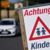 Ein Schild mit der Aufschrift "Achtung Kinder" steht an einem Straßenrand.