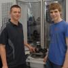 Marc Engelhard (links) und Jannik Münz (rechts) zeigen, wie sie ihre Erfindung, eine Fünf-Achs-Fräsmaschine, technisch umgesetzt haben.