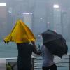 Menschen mit Regenschirmen kämpfen in Hongkong gegen starken Wind und Regen des Taifuns «Saola» an.