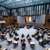 Abgeordnete stehen im Plenarsaal des Berliner Abgeordnetenhauses.