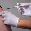 Eine Mitarbeiterin eines Impfzentrums impft einen Mann gegen Corona.