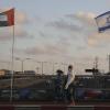 Frauen mit Schutzmasken gehen an den Flaggen von Israel und den Vereinigten Arabischen Emiraten auf der Friedensbrücke im israelischen Netanya vorbei.