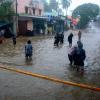 Menschen waten durch eine überschwemmte Straße nach heftigen Regenfällen an der Küste des Golfs von Bengalen.