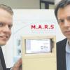 Student Christopher Proske und Professor Gundolf Kiefer präsentieren das mobile Schulungsgerät Mars. Es erkennt über eine Kamera vorher „gelernte“ Gegenstände und kann dann einzelne Bauteile dieser Gegenstände benennen und Anweisungen dazu geben.  