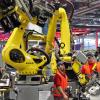 Mechatroniker installieren einen Kuka-Roboter in einem Porsche-Werk.