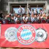 Spielerinnen und Spieler von Bayern München jubeln auf dem Rathaus-Balkon.