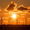 In Schleswig-Holstein strahlt die untergehende Abendsonne auf einen Windpark am Bredstedter Koog. Mehr Windkraft- und Solaranlagen sind der beste Weg hinzu stabilen Energiepreisen.