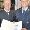 Das Steckkreuz, die höchste Form des Feuerwehr-Ehrenzeichens, und eine Urkunde hat Kreisbrandrat Frank Schmidt (rechts) in Augsburg von Regierungspräsident Karl Michael Scheufele (links) überreicht bekommen.  