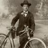 Ein stolzer Radler: Dieser junge Mann nahm sein Fahrrad mit zum Fotografen und ließ sich um 1907 vor gemalter Landschaft fotografieren. 	