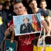 Ein Flüchtling läuft mit einem Foto von Angela Merkel in den Händen über den Bahnsteig. Die Bundeskanzlerin ist für viele Flüchtlinge die Figur der Hoffnung.
