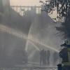 Feuerwehrleute löschen brennende Häuser, die durch einen Böschungsbrand direkt an der wichtigen Bahnstrecke Köln-Frankfurt in Brand geraten waren.