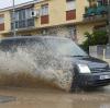 Ein Auto fährt durch aufgestautes Wasser in einer Straße in Villamanta.