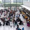 Passagiere stehen am Flughafen München an einem Check-in-Schalter. Flugreisen sind auch heute nicht selbstverständlich, sondern mit harter Arbeit verbunden. 